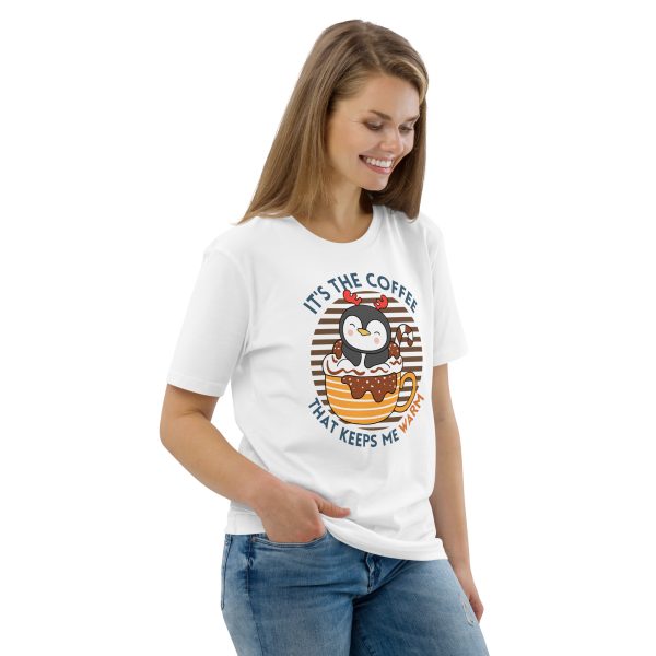 Penguin drinking coffee and taking bath in a coffee mug looking happy and cosy design on a t-shirt worn by a woman smiling with her right hand on her pocket while looking down. The photograph represents her front-right part.