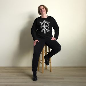 Woman posing smilling and wearing a black sweatshirt with skeleton ribcage design effect organic cotton